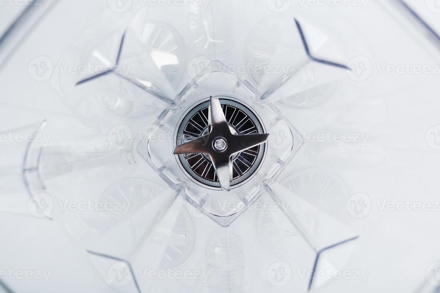 Close-up of a blender glass shot from the inside with sharp stainless steel blades in the center. photo