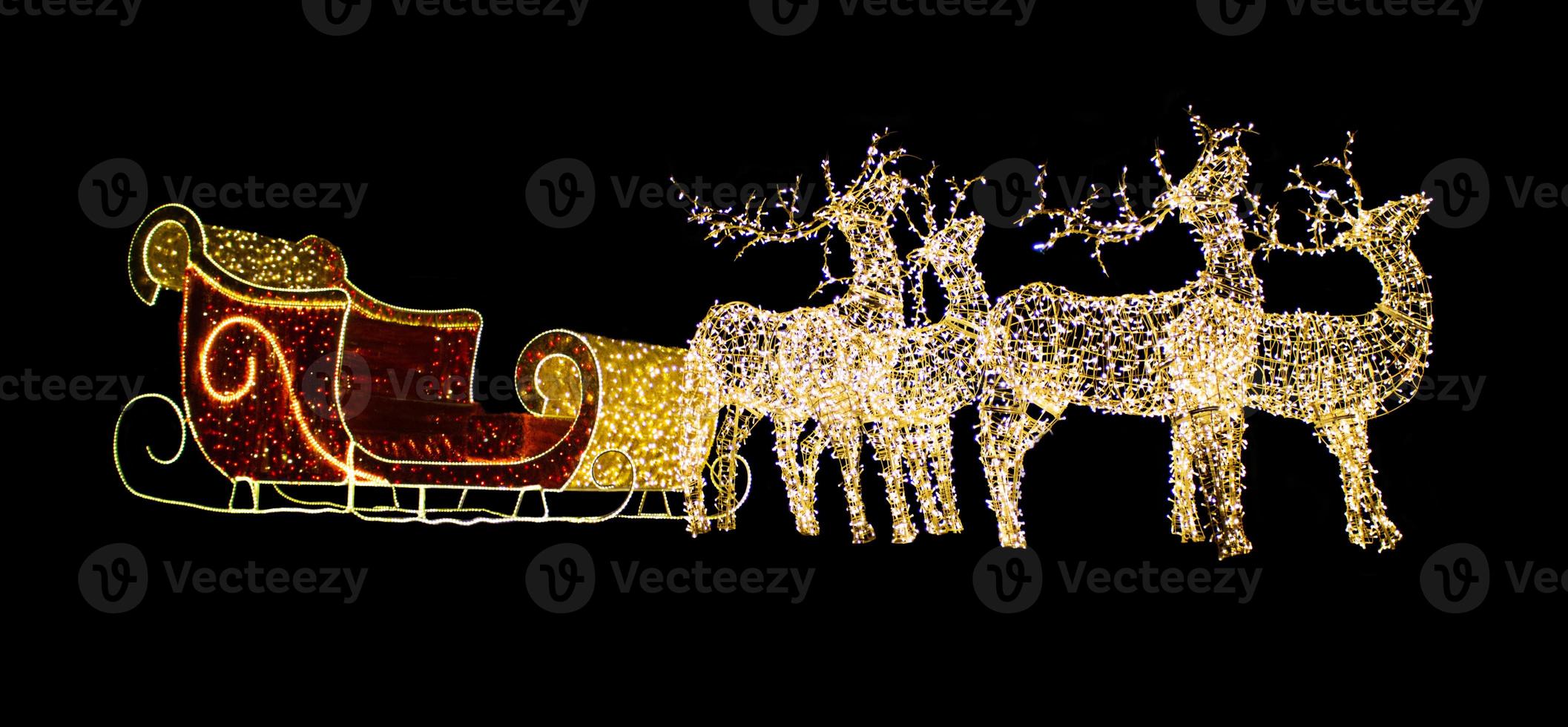 Christmas reindeer from light bulbs with red sleigh of Santa Claus on a black isolated background. Christmas, New Year. Copy space photo