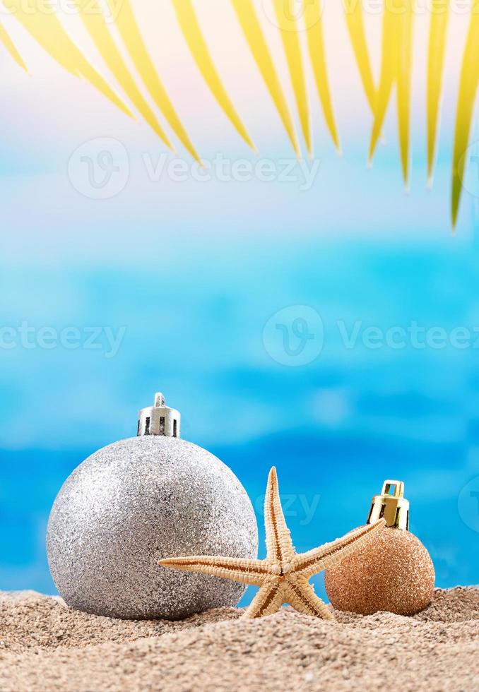 bolas de brillo con estrellas de mar, palmeras en la playa en tropical. concepto de navidad, vacaciones de año nuevo en países cálidos. copie el espacio foto