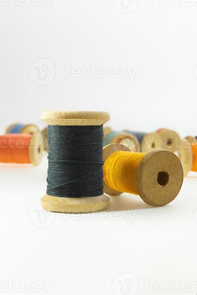 Wooden bobbins for black, yellow,  threads on white isolated background. Handmade, needlework, sewing items. Copy space photo