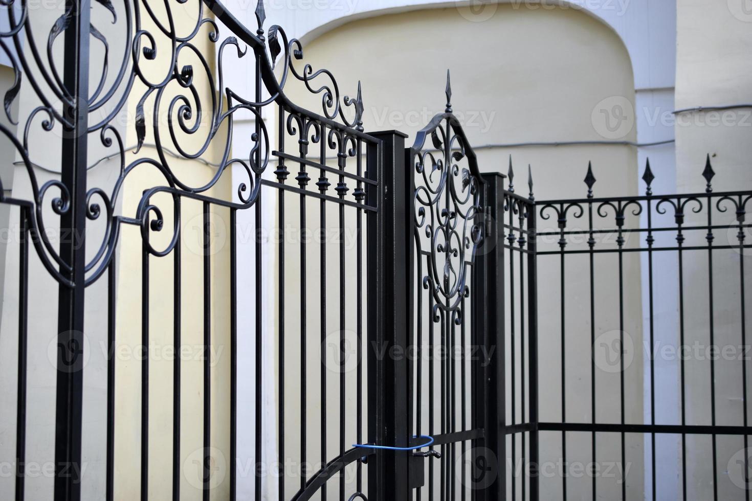 A classic yellow house and a beautiful iron fence with a gate. photo