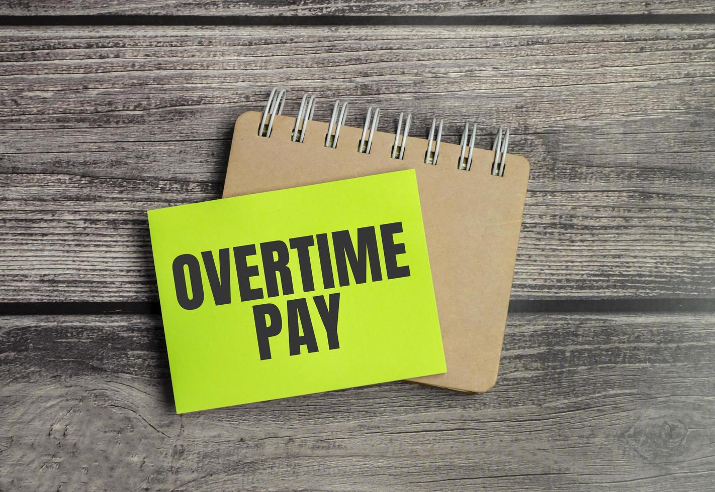 overtime pay words and green sticker on wooden background photo