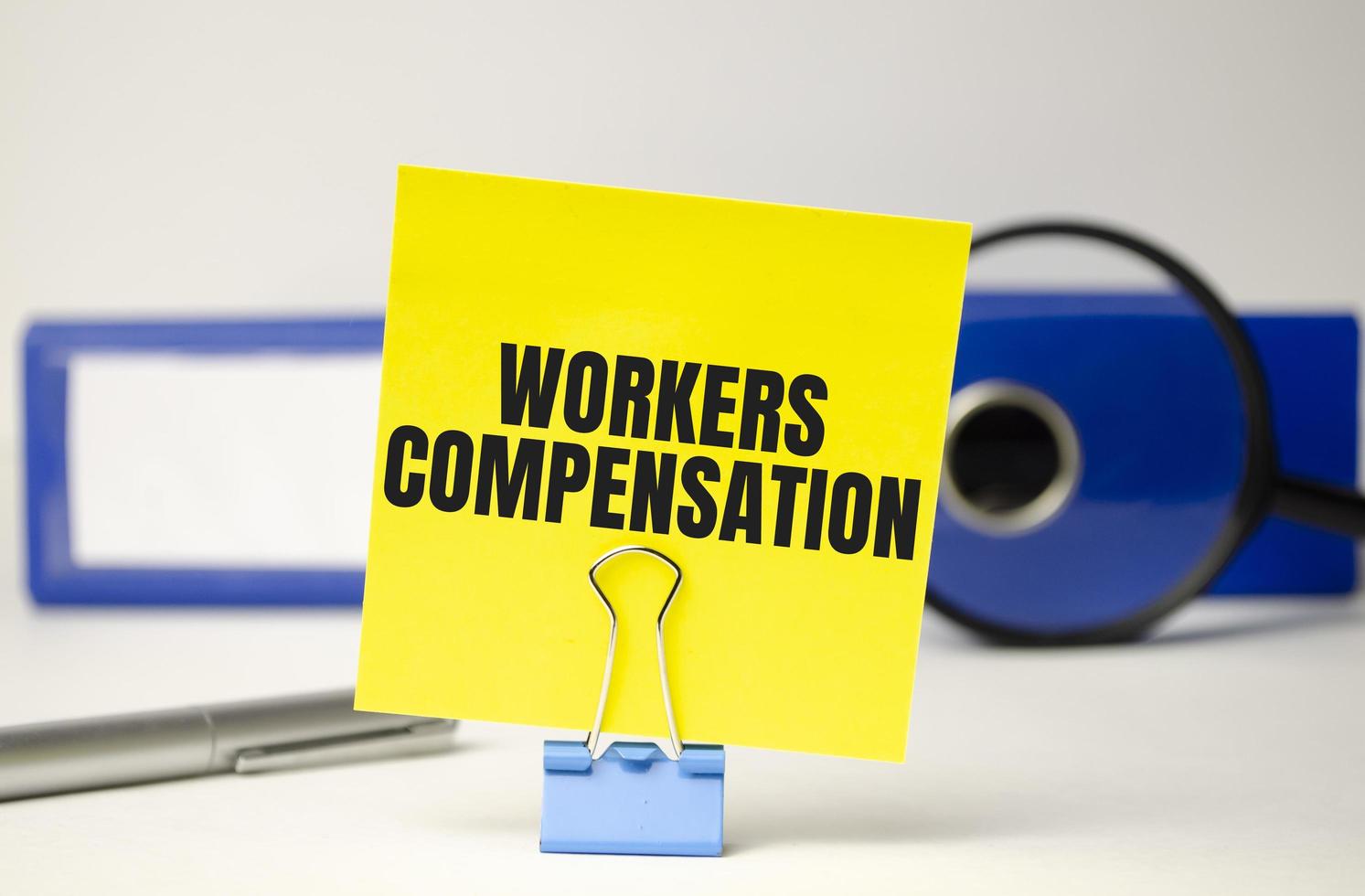 Workers compensation on yellow sticker and blue file folder photo