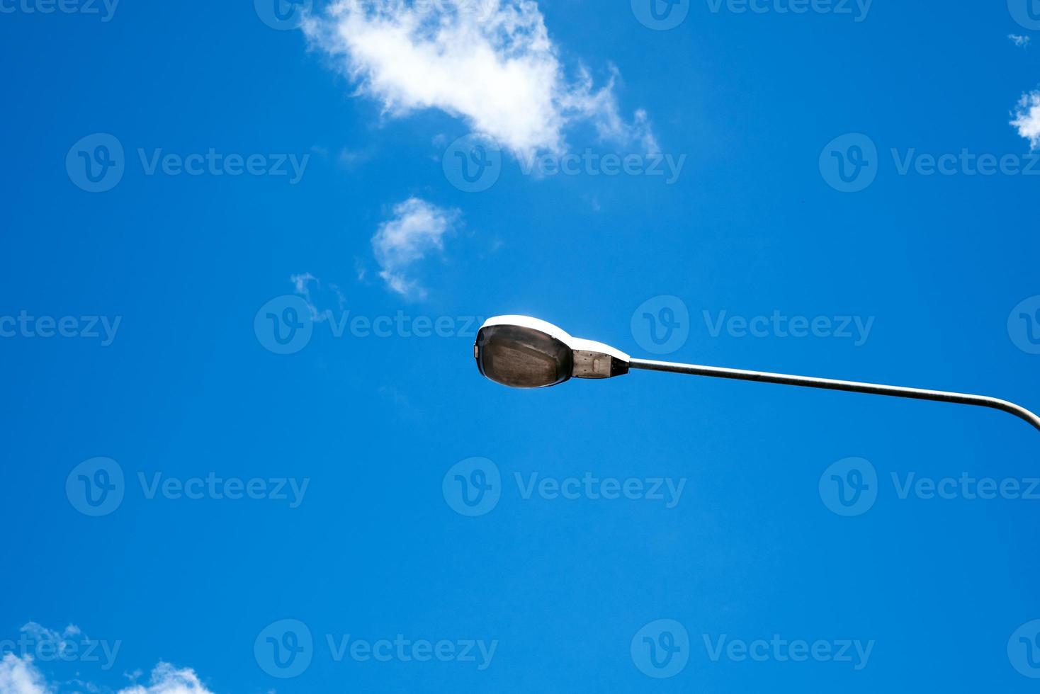 Modern electricity lamp post with blue sky and cloud as background. Steel street light or lantern on pole in the daytime are conceptualized in industrial, technological, and urbanize photo