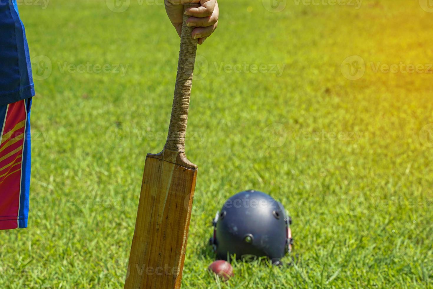 A clicket player holds a bat in his hand while the game is on the sidelines. Soft and selective focus. photo