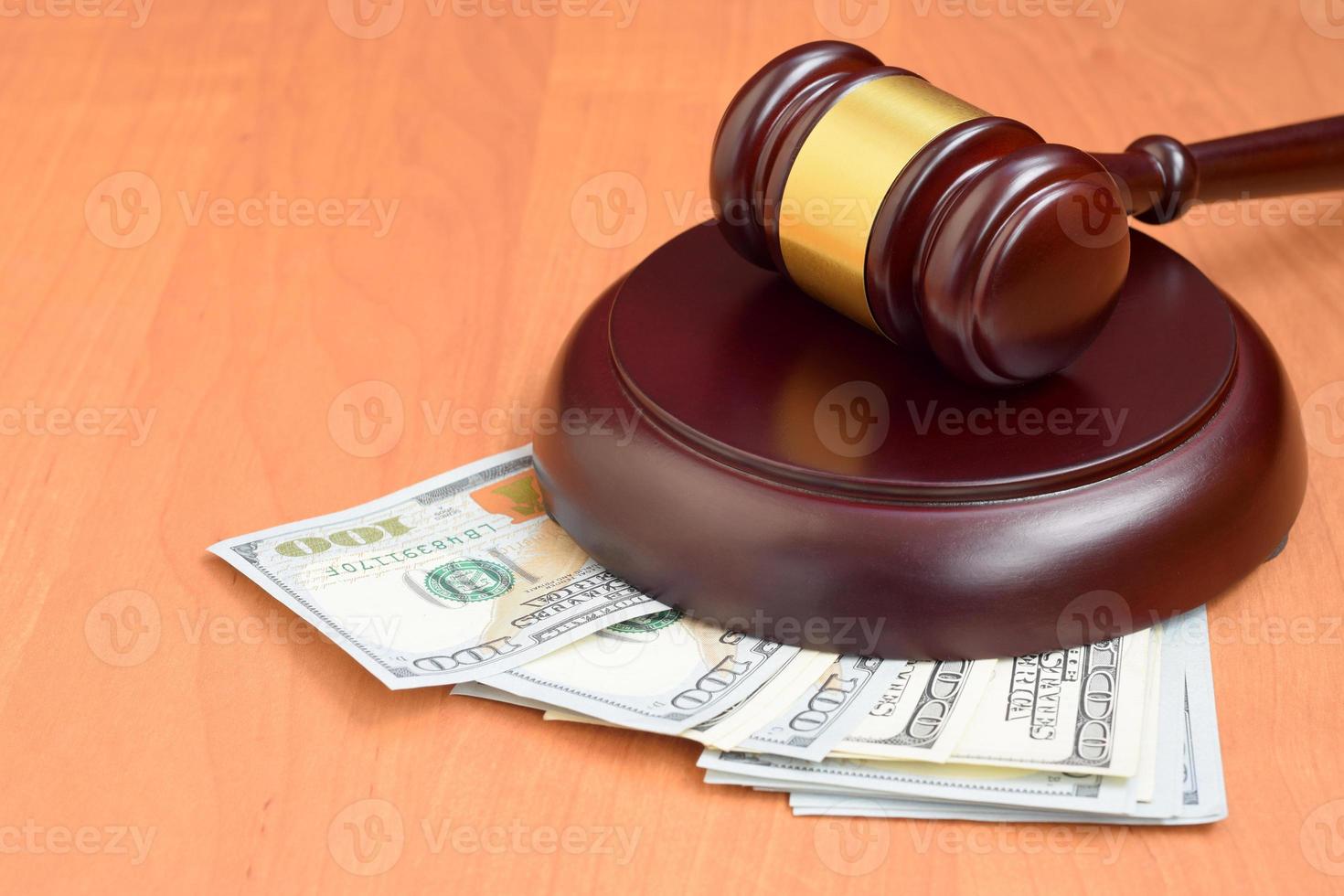 mazo de juez y dinero en una mesa de madera marrón. muchos billetes de cien dólares bajo la malicia del juez en el escritorio de la corte. juicio y soborno foto