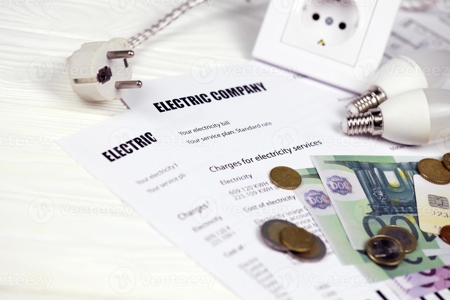 Calculator and Euro bills with pen on european electricity bill. Concept of saving money by using energy savings led light bulbs and electric bill payment photo