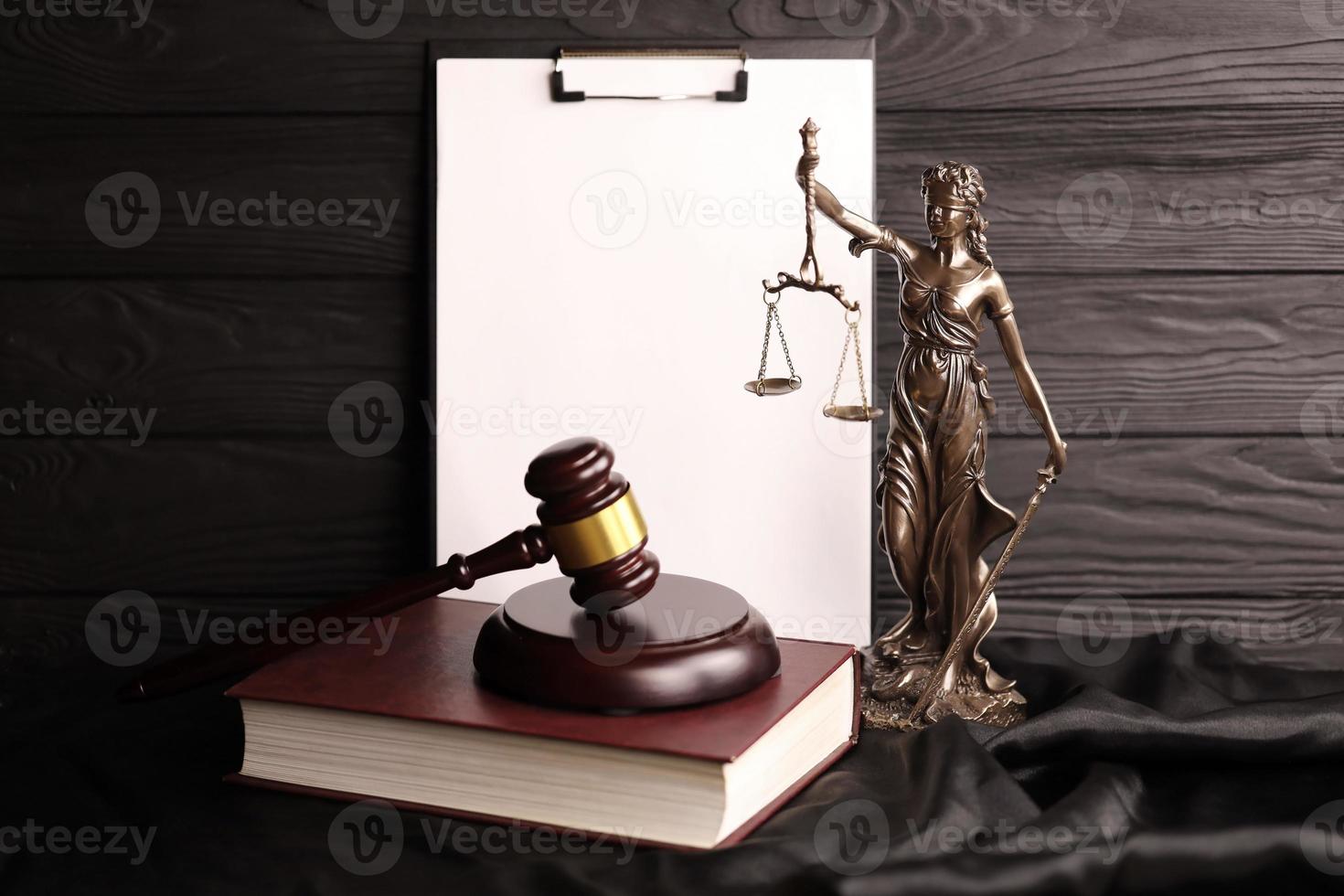 Lady justice or justitia the Roman goddess of Justice. Statue on brown book with judge gavel on blank paper background with copyspace. Concept of judicial trial, courtroom process and lawyers work photo