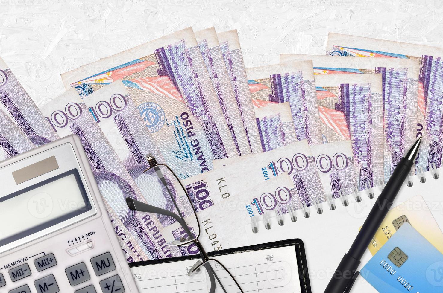 100 Philippine piso bills and calculator with glasses and pen. Tax payment concept or investment solutions. Financial planning or accountant paperwork photo