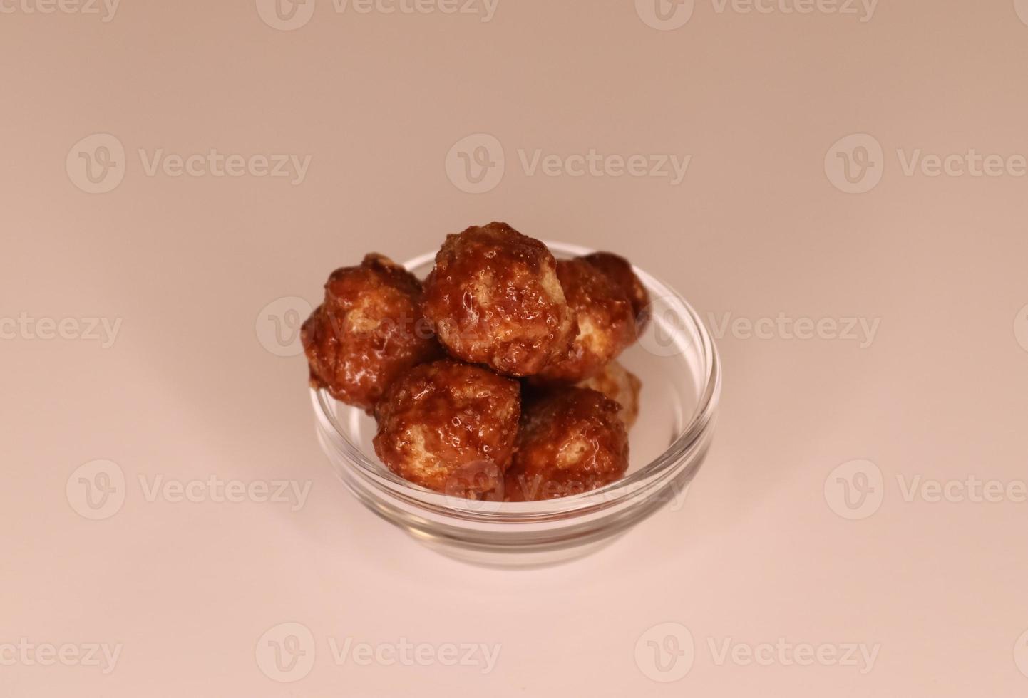 Selective focus of many candied macadamia nuts spinning in a small bowl. photo