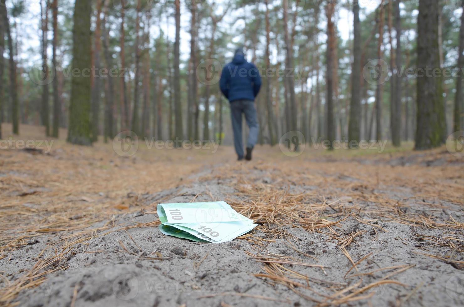 Young man loses his euro money bills on Russian autumn fir wood path. Carelessness and losing money concept photo