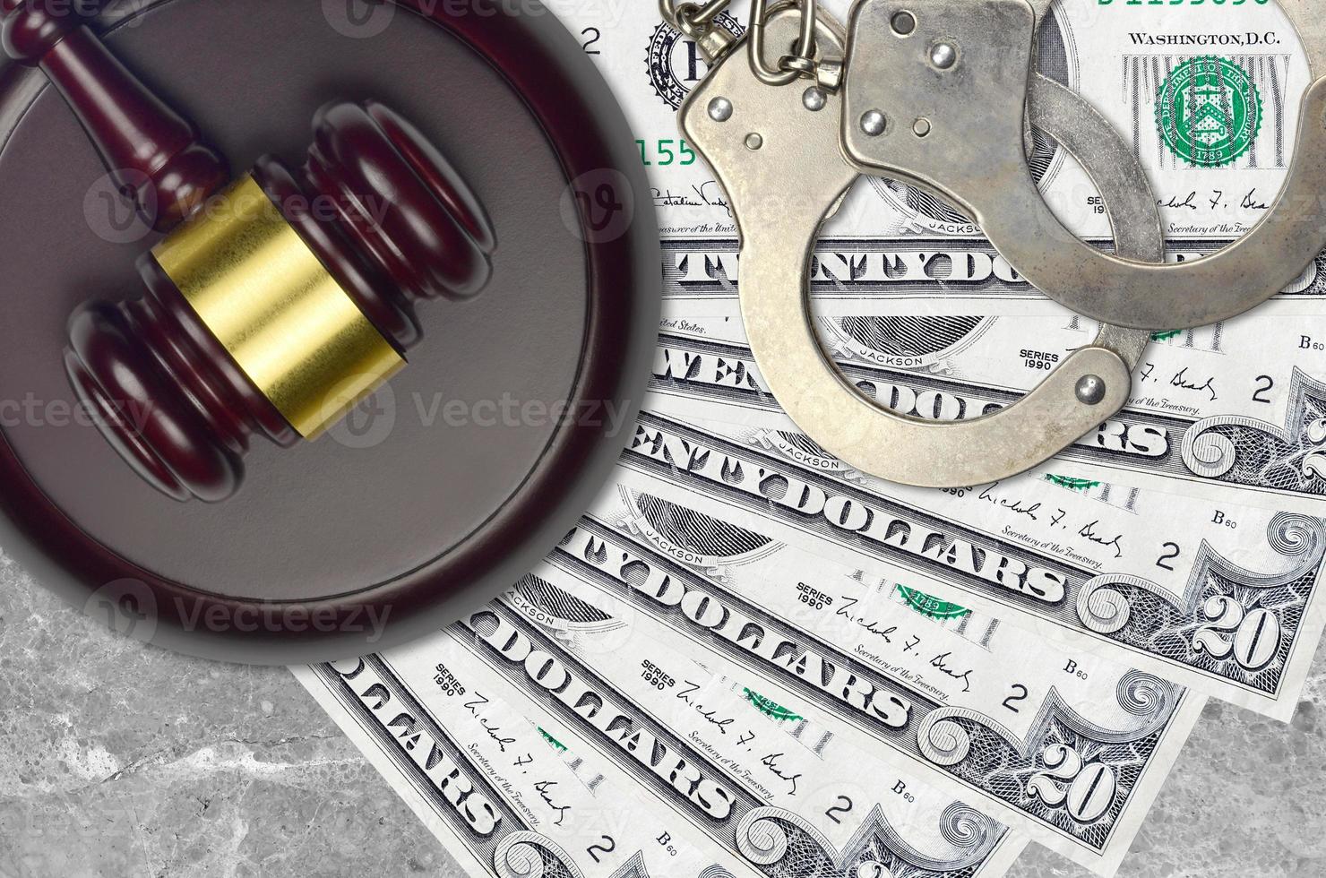 20 US dollars bills and judge hammer with police handcuffs on court desk. Concept of judicial trial or bribery. Tax avoidance photo