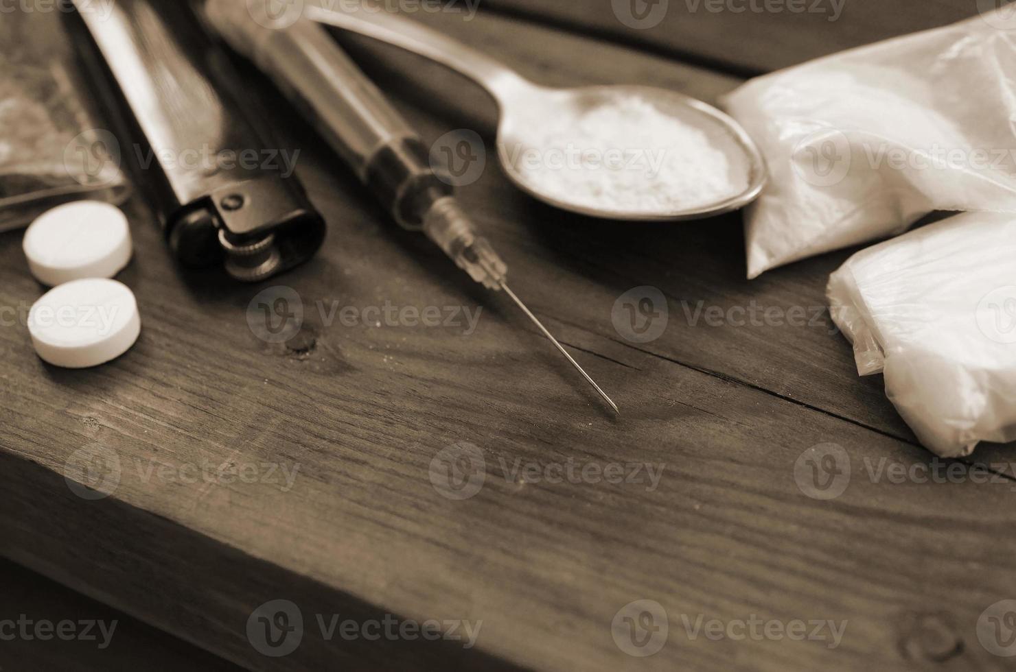 A lot of narcotic substances and devices for the preparation of drugs lie on an old wooden table photo