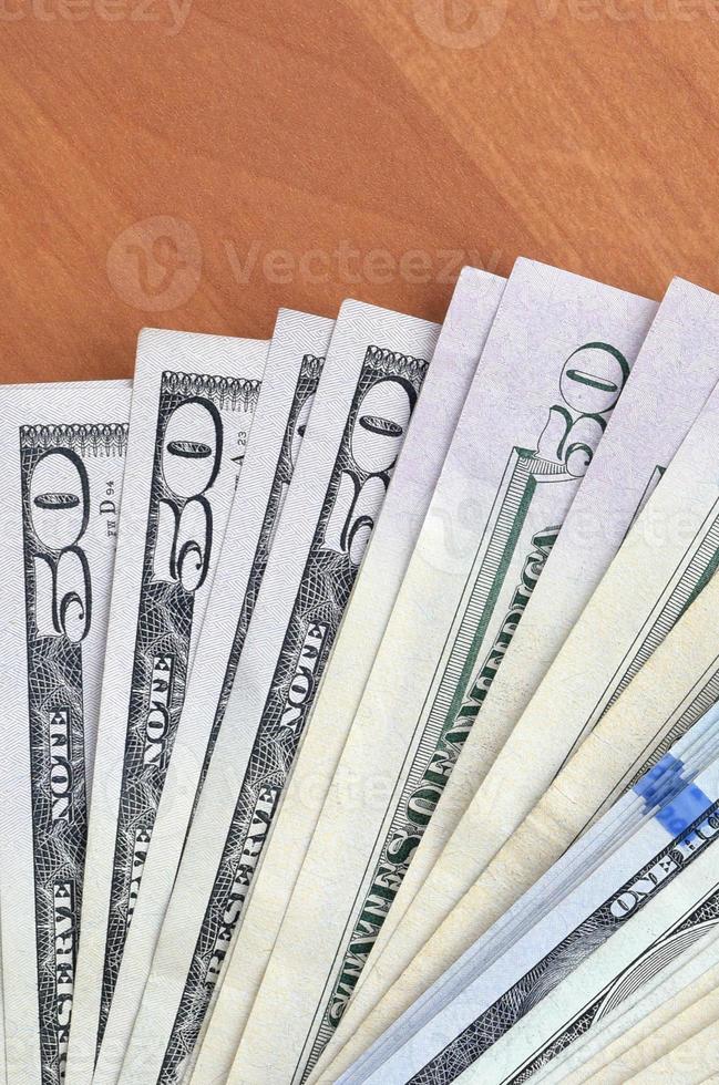 Fan of many one hundred and fifty dollar bills on wooden background surface close up. Flat lay top view. Abstract business concept photo