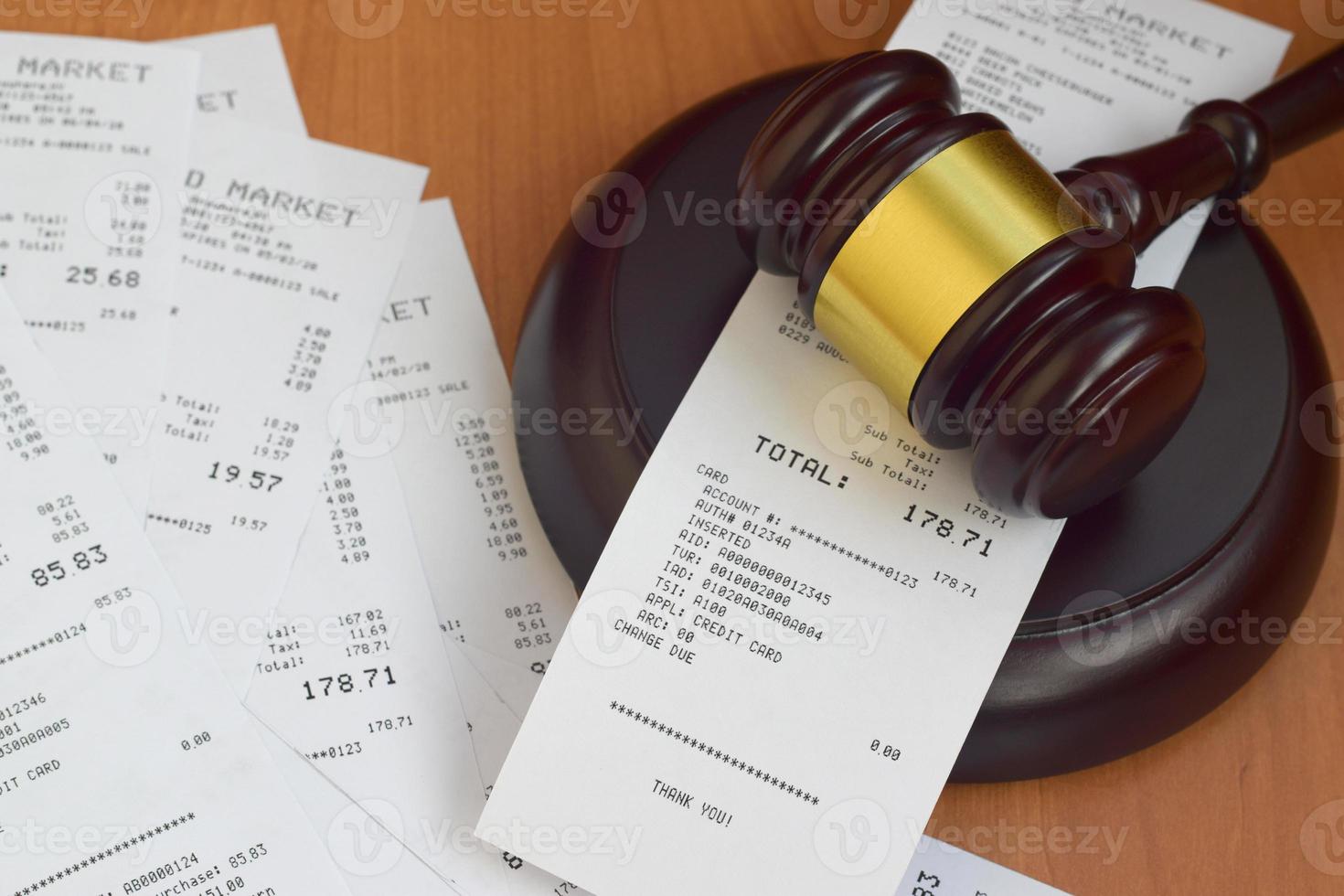 Justice mallet and many supermarket receipts on wooden table photo