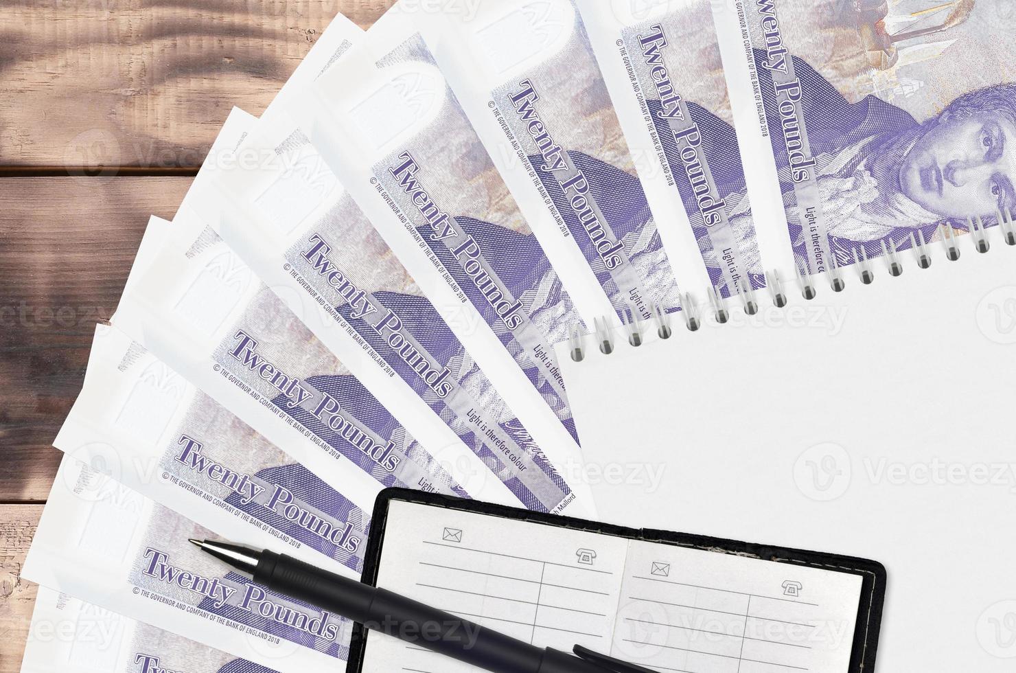 20 British pounds bills fan and notepad with contact book and black pen. Concept of financial planning and business strategy photo