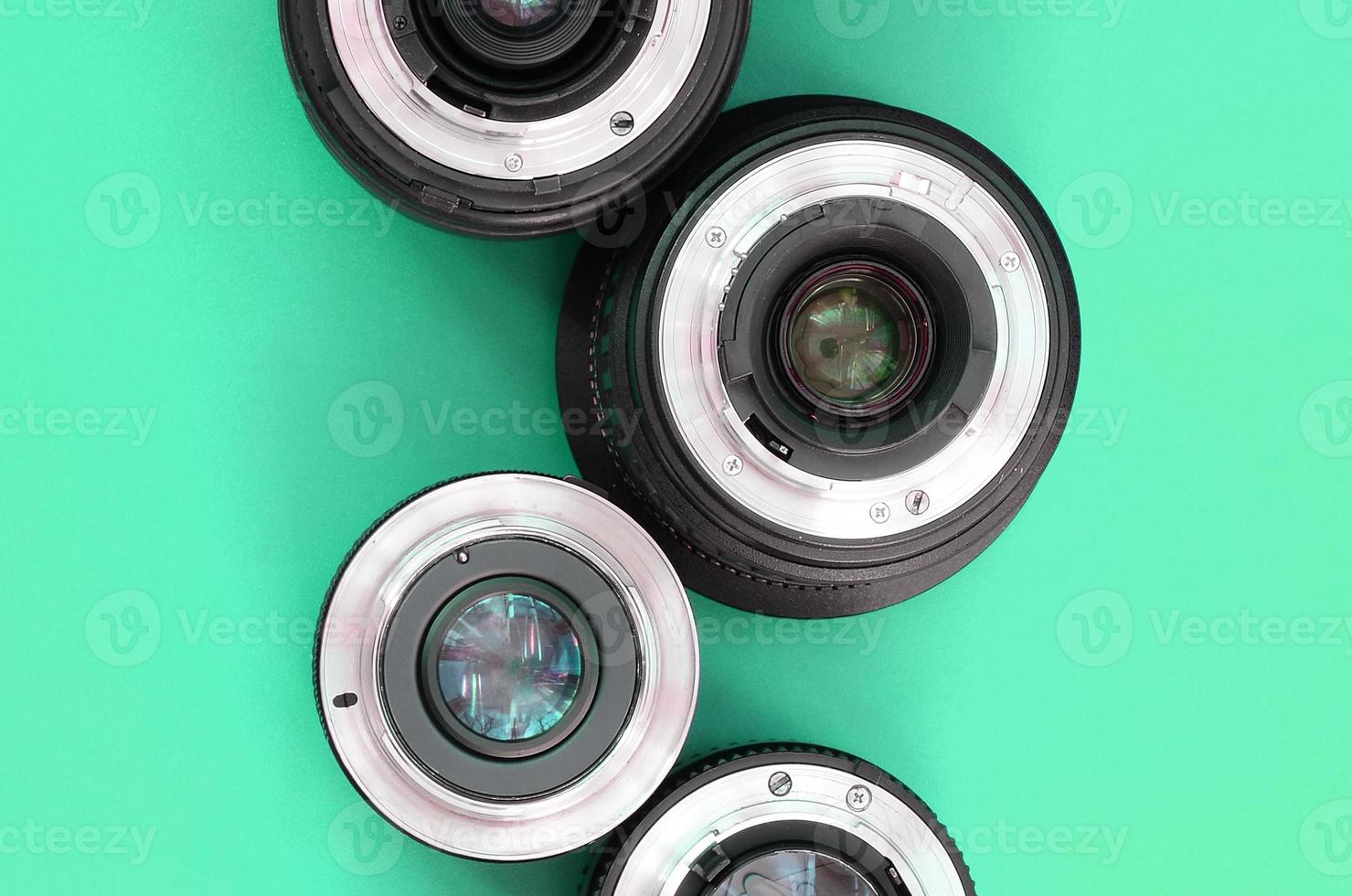Several photographic lenses lie on a bright turquoise background. Copy space photo