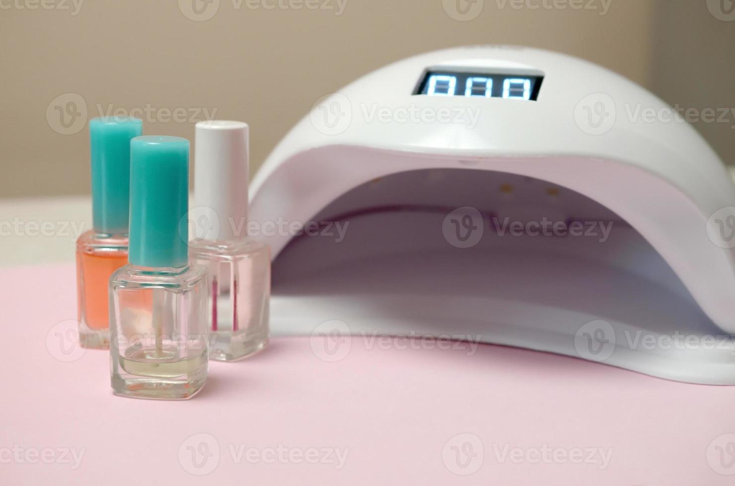 luces de lámpara de diodo uv para uñas y juego de esmalte de uñas cosmético para manicura y pedicura sobre fondo pastel foto