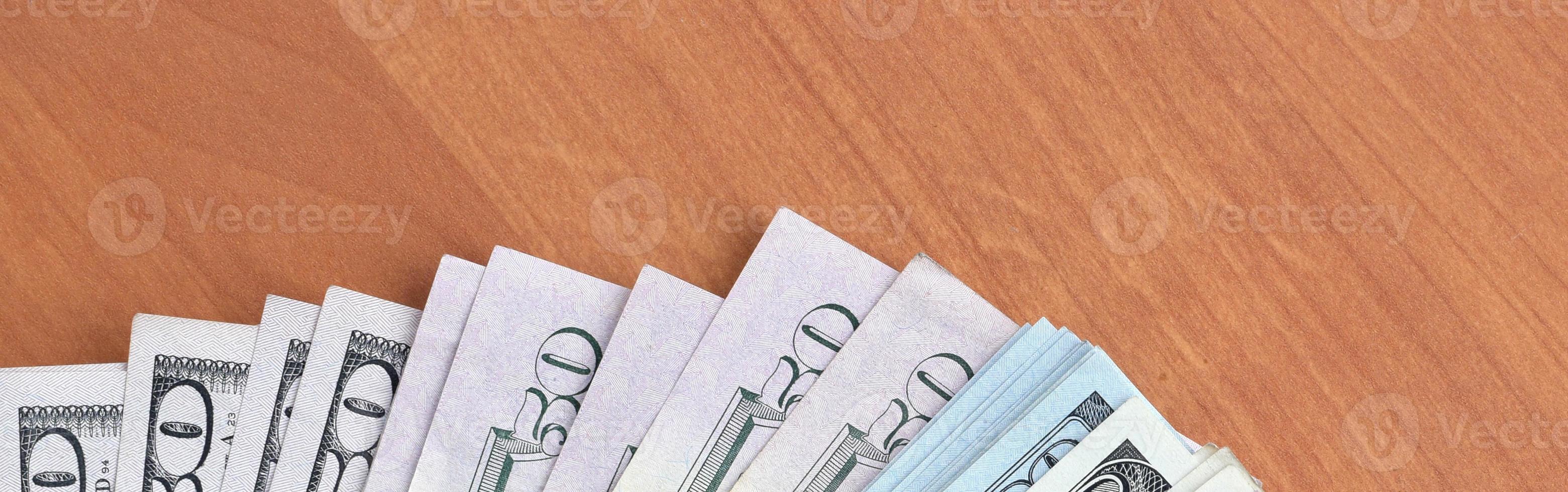Fan of many one hundred and fifty dollar bills on wooden background surface close up. Flat lay top view. Abstract business concept photo