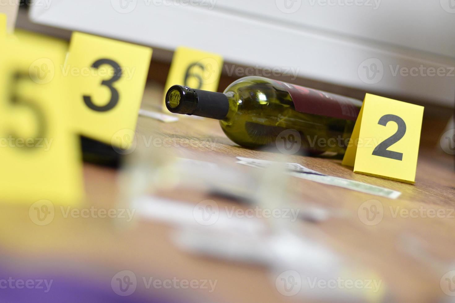 Broken glass and bottle of wine marked as evidence during crime scene investigation. Many yellow markers with numbers photo