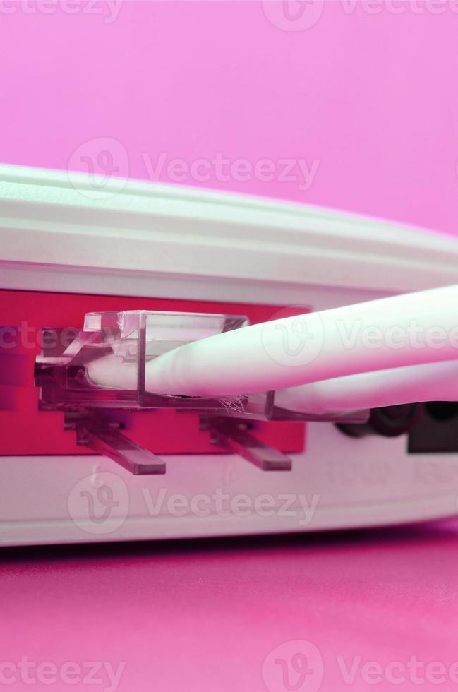The Internet cable plugs are connected to the Internet router, which lies on a bright pink background. Items required for Internet photo