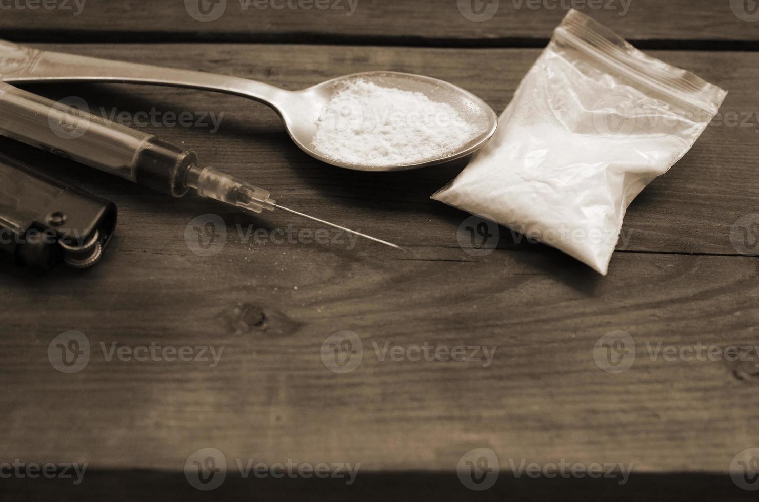 Syringe lighter and spoon full of white powder on wooden background. Heroin drug addiction concept photo