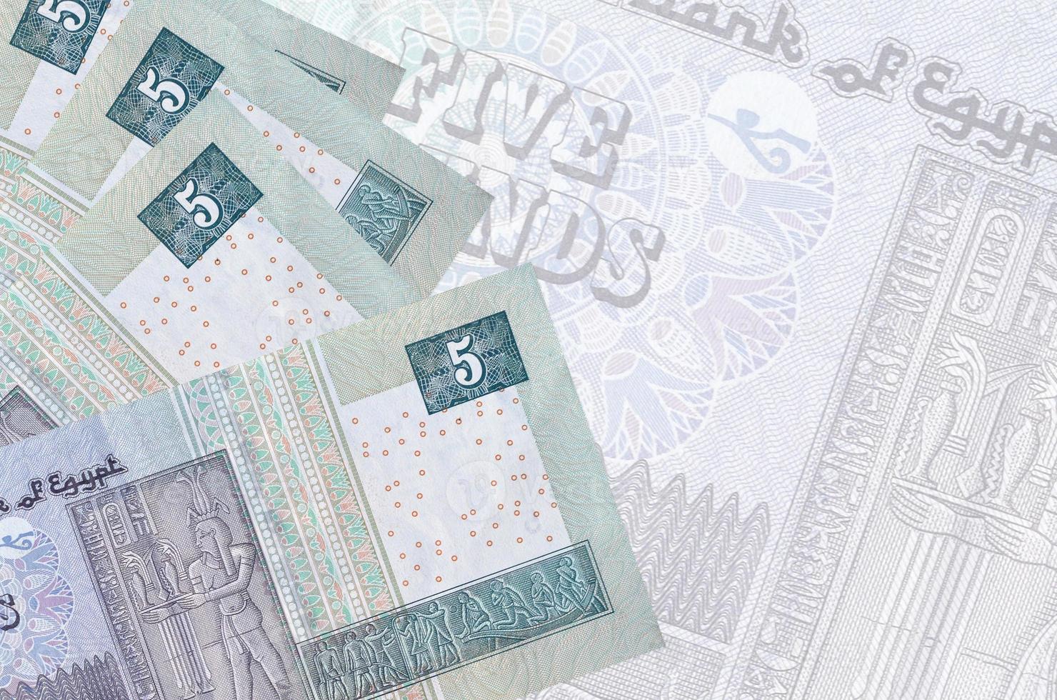 5 Egyptian pounds bills lies in stack on background of big semi-transparent banknote. Abstract business background photo