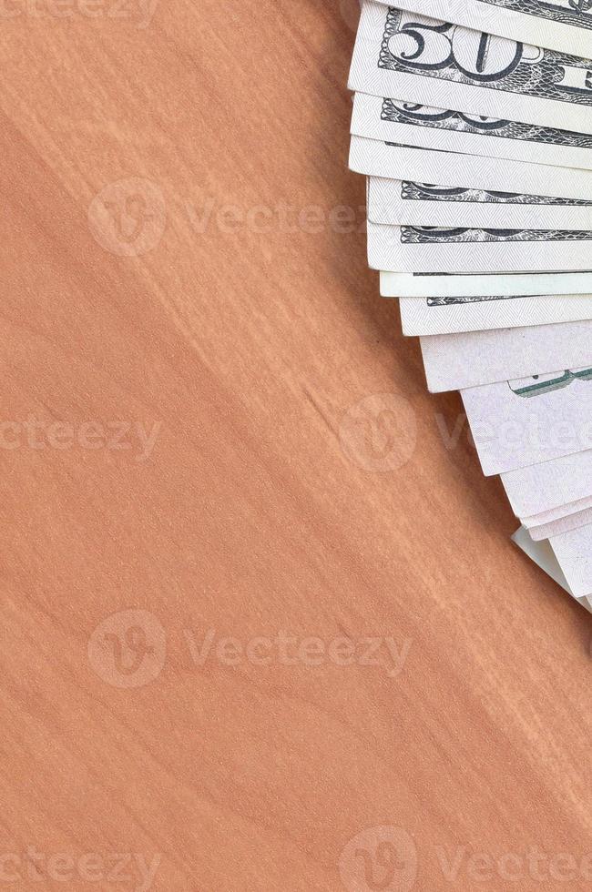 Fan of many one hundred and fifty dollar bills on wooden background surface close up. Flat lay top view. Abstract business concept photo