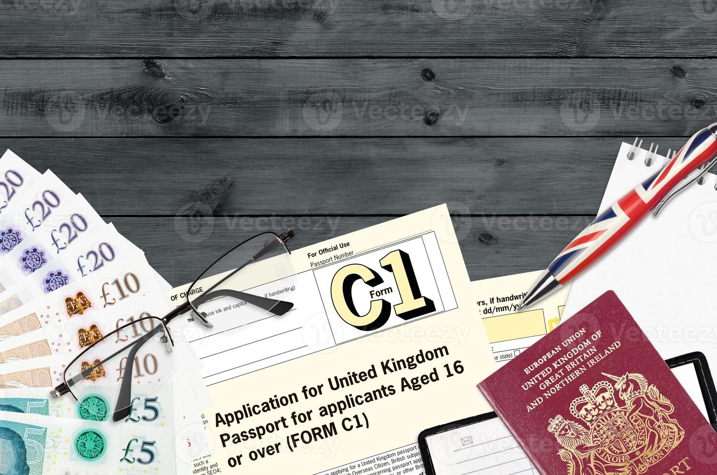 English form C1 Application for United Kingdom passport for applicants aged 16 or over lies on table with office items. UK passport paperwork photo