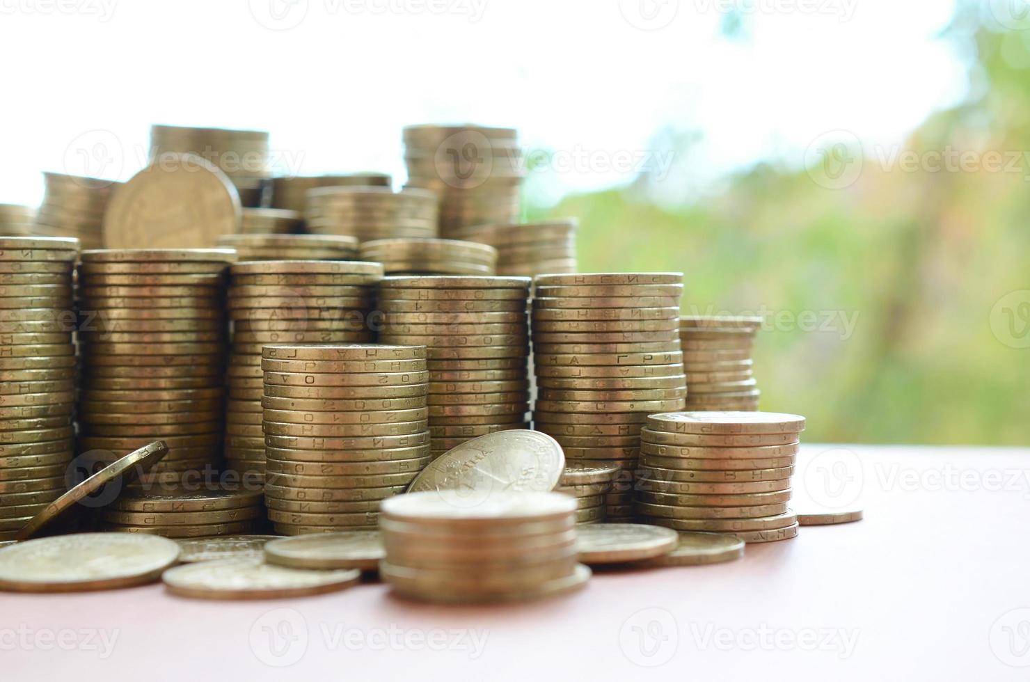 Big amount of shiny ukrainian old 1 hryvnia coin stacks close up on wooden table on green trees backdrop. The concept of business and rich life in Ukraine photo