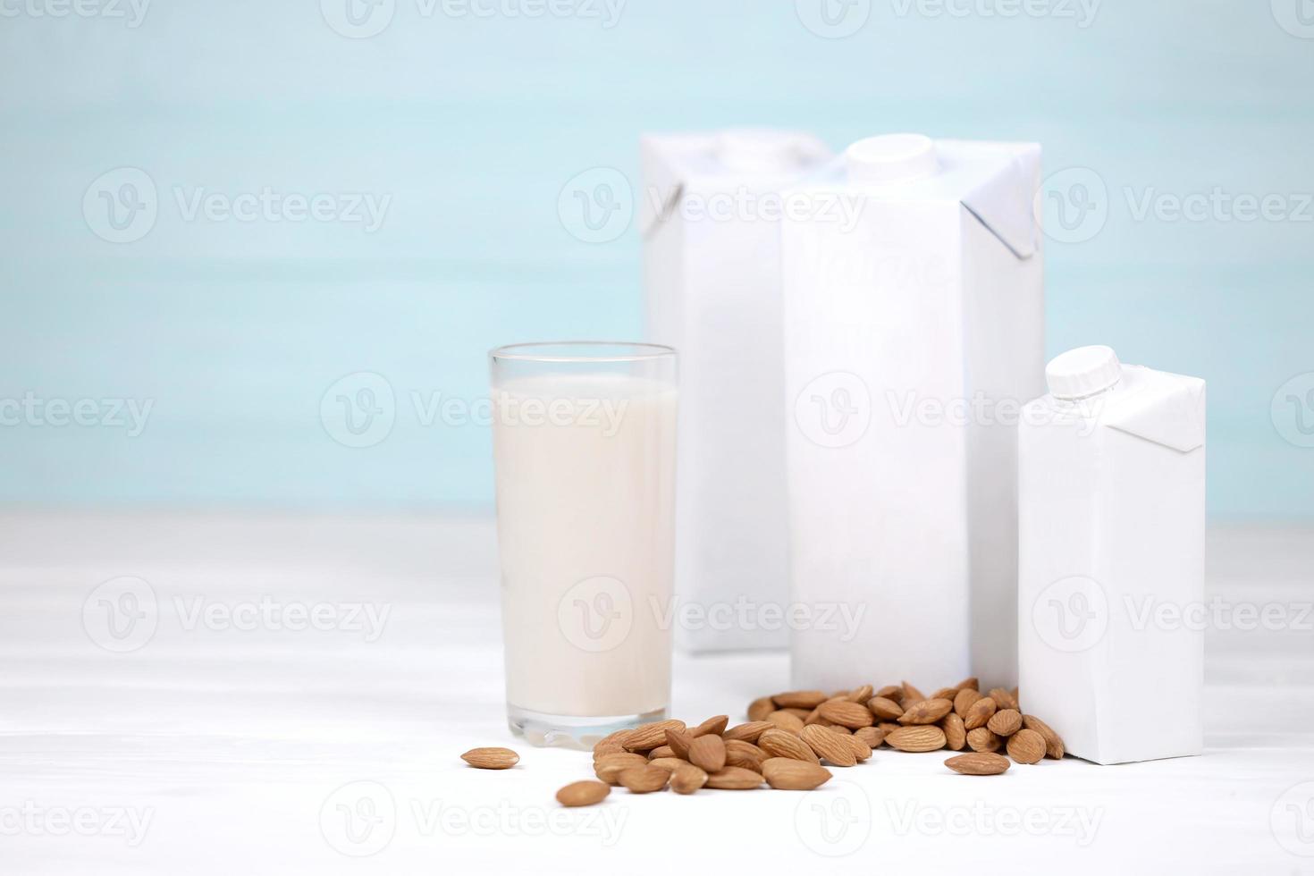 Glass of almond milk with almond nuts on canvas fabric on white wooden table. Dairy alternative milk for detox, healthy eating and diets photo