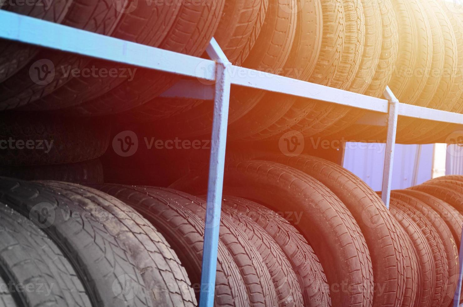 Rack with variety of car tires in automobile store. Many black tires. Tire stack background photo