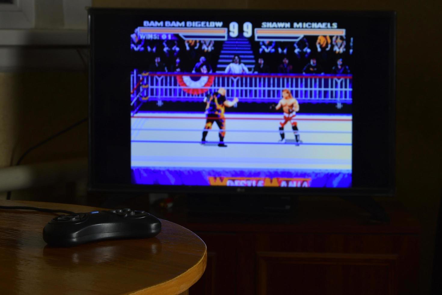 KHARKOV, UKRAINE - NOVEMBER 12, 2020 Sega mega drive video game controller on table with Wrestlemania game on display photo