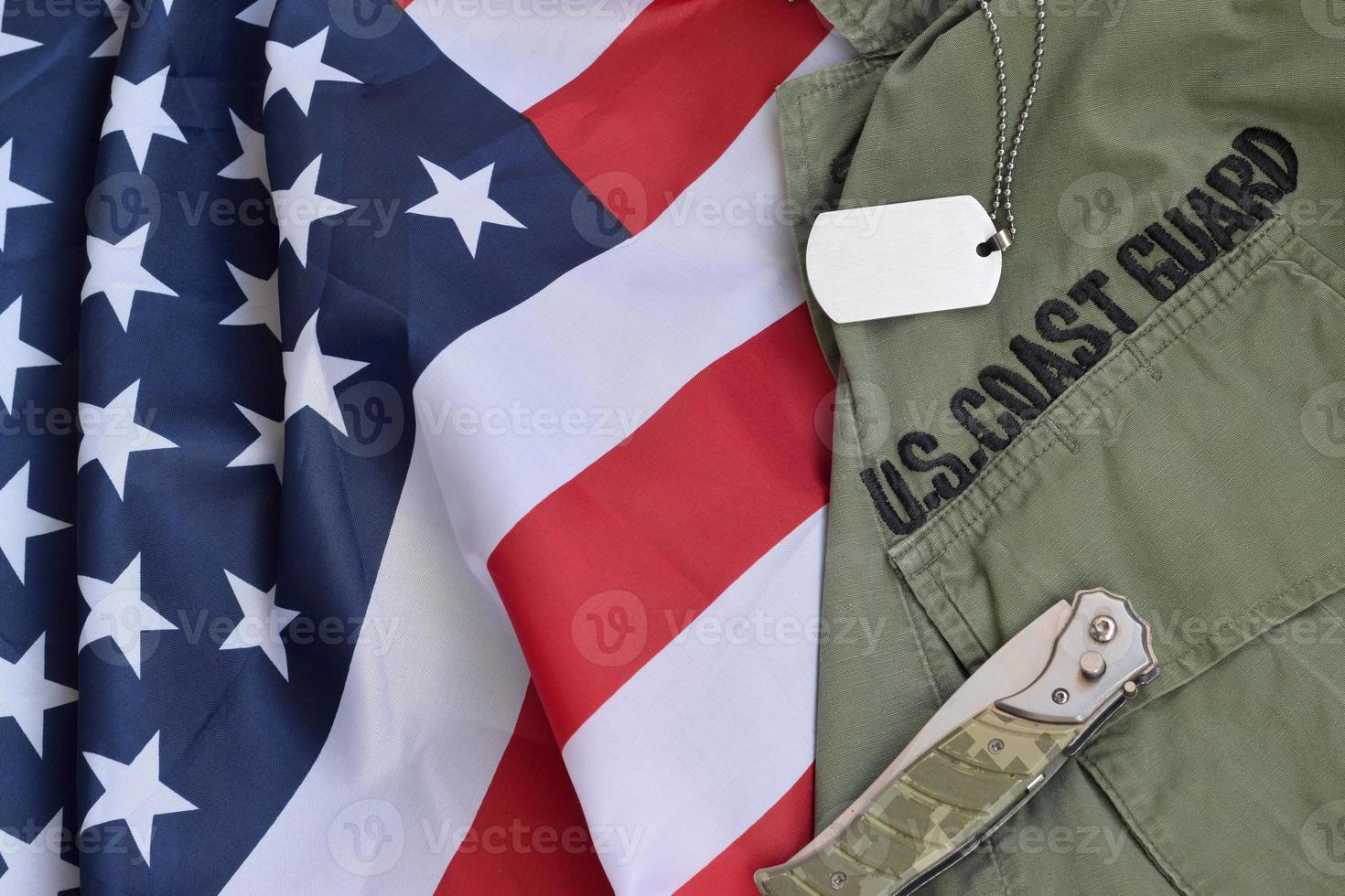 la ficha de identificación militar y el cuchillo se encuentran en el viejo uniforme de la guardia costera estadounidense y en la bandera doblada de los Estados Unidos foto