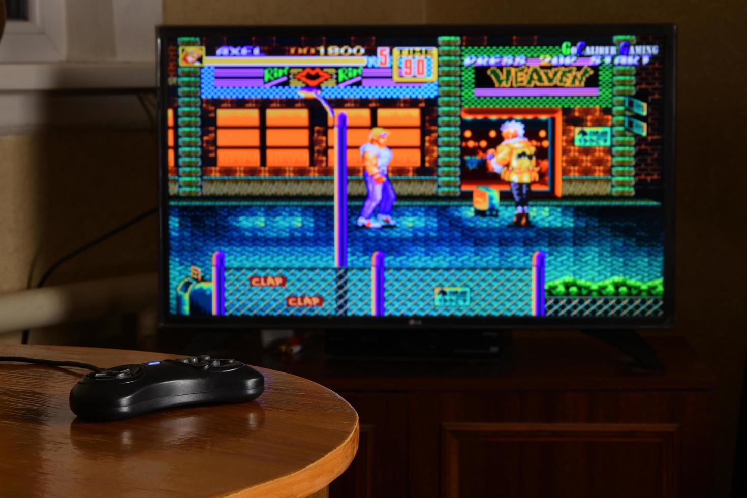 KHARKOV, UKRAINE - NOVEMBER 12, 2020 Sega mega drive video game controller on table with Streets of Rage 2 game on display photo