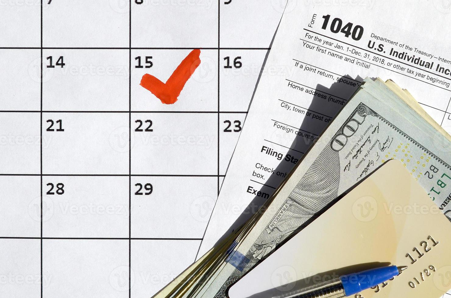 1040 Individual Income Tax Return blank with credit card on dollar bills and pen on calendar page with marked 15th April photo