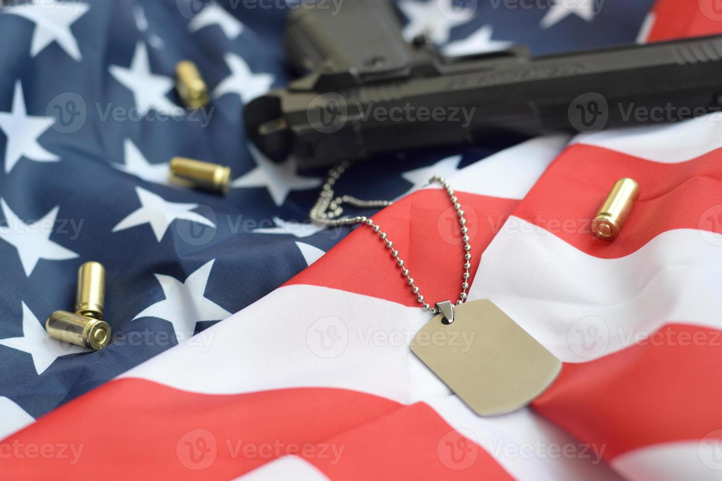 Army Dog tag token with 9mm bullets and pistol lie on folded United States flag photo