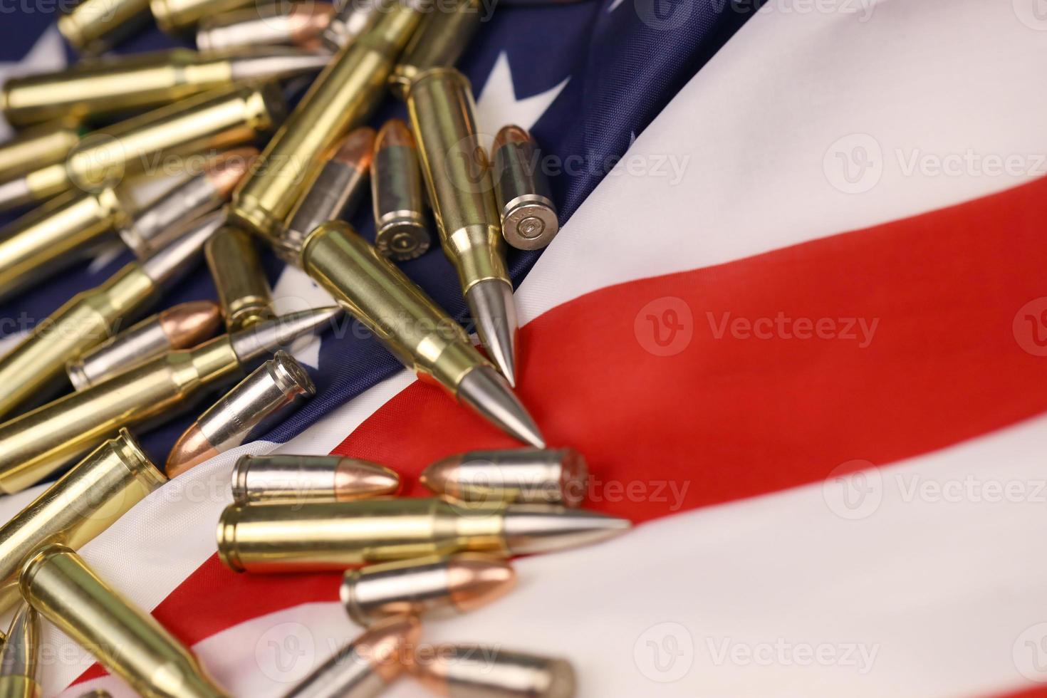 Many yellow 9mm and 5.56mm bullets and cartridges on United States flag. Concept of gun trafficking on USA territory or special ops photo