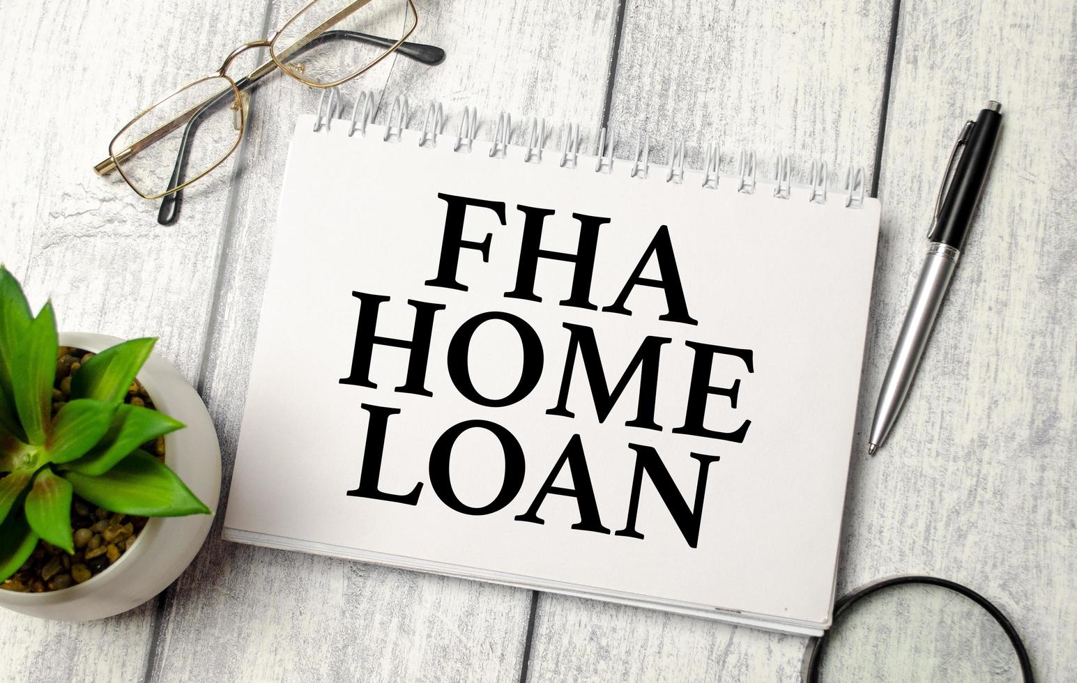 words FHA Home loan on notepad and pen, glasses on wooden background photo