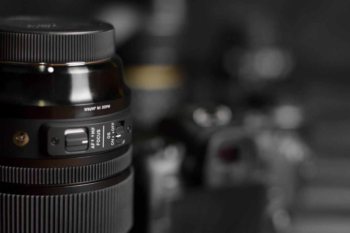 Sigma 24-105 f4 Art lens with Canon EOS R photocamera and other Canon lenses on black wooden table. Photography equipment by Sigma for Canon. photo