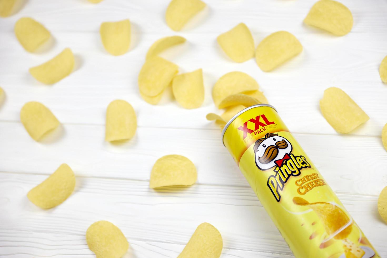 Pringles cheesy cheese flavour. Cardboard tube can with Pringles potato chips on white table. Pringles is a brand of potato snack chips owned by Kellogg Company photo