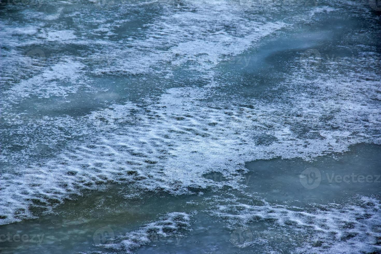 Winter background of the icy surface of the river. Texture of ice covered with snow. photo