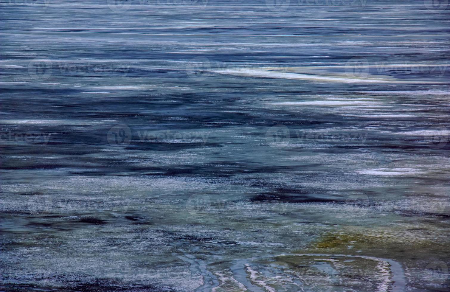 Winter background of the icy surface of the river. Texture of ice covered with snow. photo