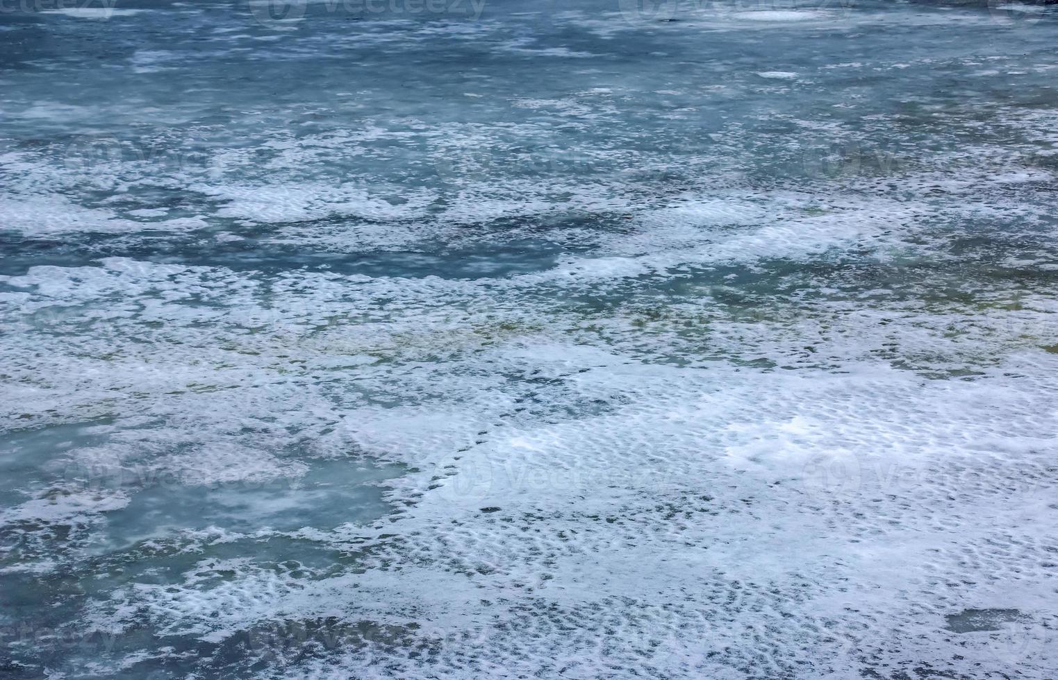 Winter background of the icy surface of the river. Texture of ice covered with snow. photo