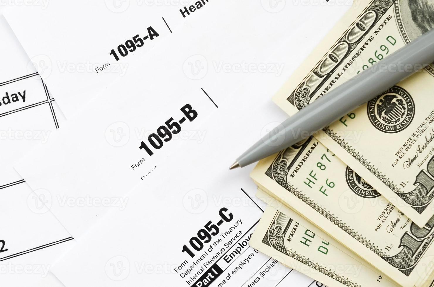 IRS Form 1095-A 1095-B and 1095-C blank lies on empty calendar page with pen and dollar bills photo