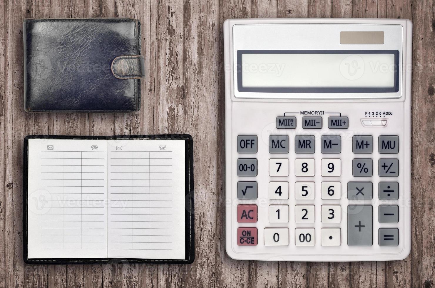 Office flat lay composition with calculator, address book and black purse on brown wooden table background with top view. Accountant paperwork concept photo