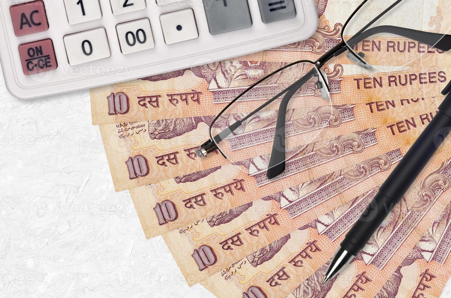 10 Indian rupees bills fan and calculator with glasses and pen. Business loan or tax payment season concept photo