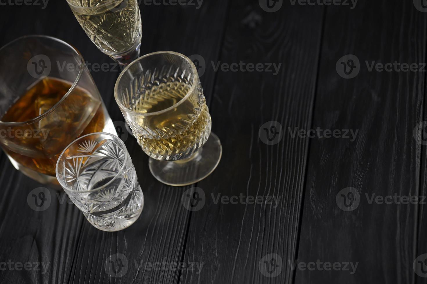 Different alcohol drinks in glass on wooden surface on dark background. Luxury elite alcohol in glass cups. Low key scene photo