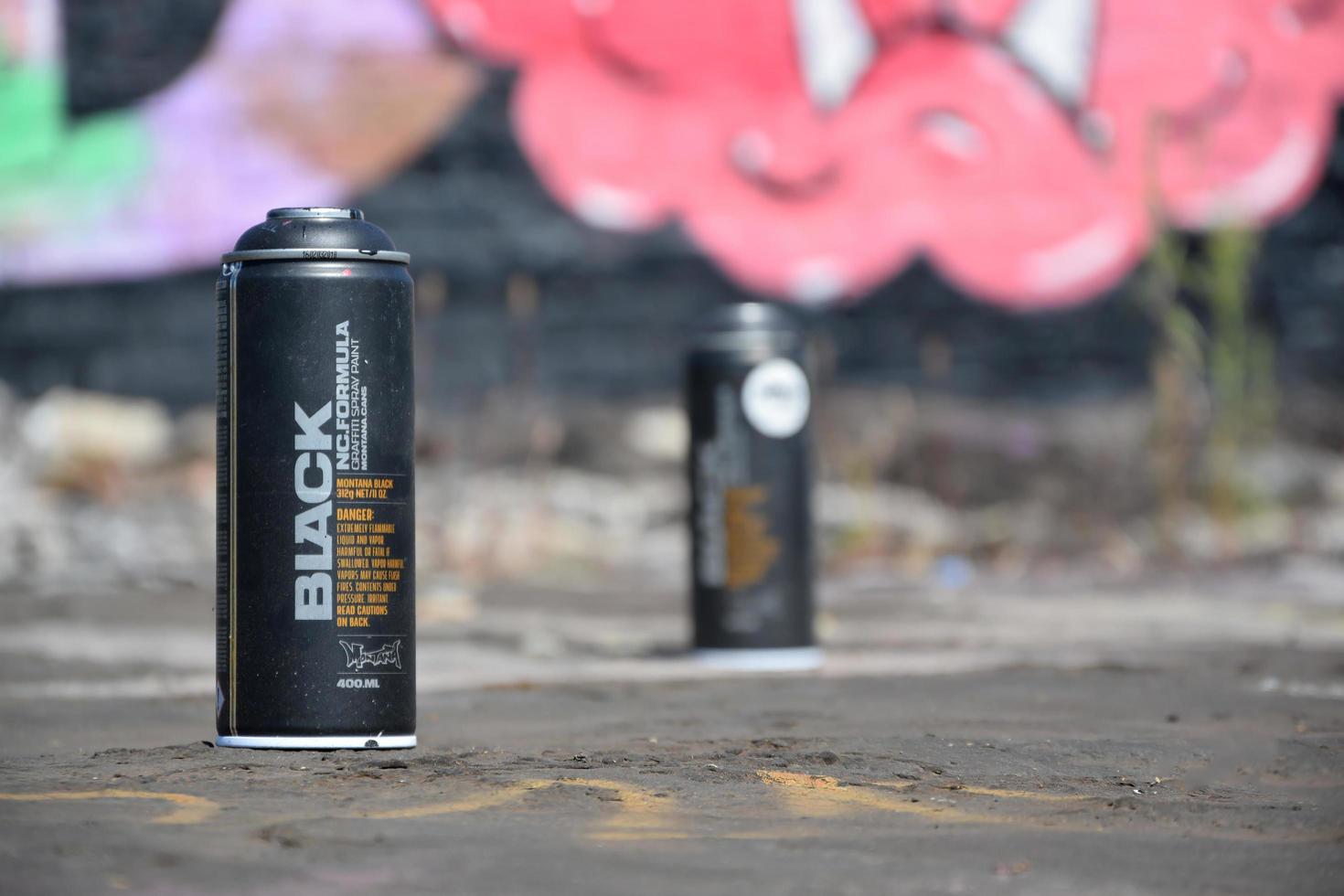 Used Montana black aerosol spray cans against graffiti paintings. MTN or Montana-cans is manufacturer of high pressure spray paint goods photo