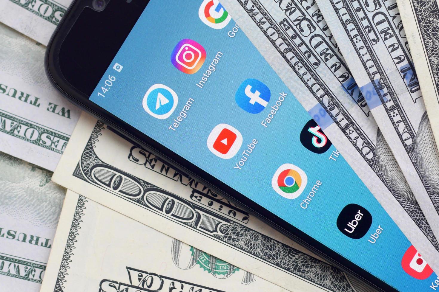 Smartphone screen with many popular apps and lot of hundred dollar bills. Business and social networking concept photo